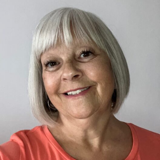 Lady with a grey bob haircut smiles at the camera