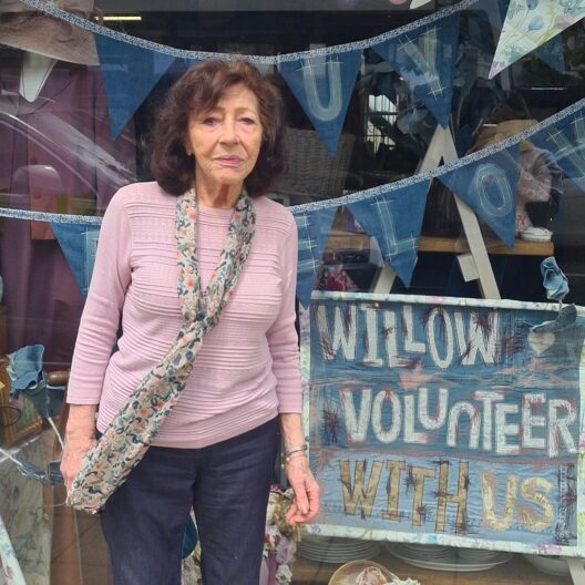 Lady in a pink t-shirt stands in front of a shop window