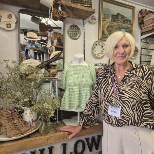 A lady stands in a shop, smiling