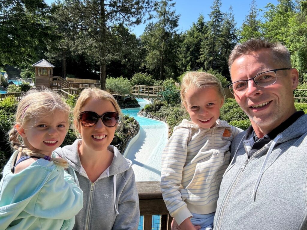 A picture of a mum, dad and two children smiling at the camera on a special day out together