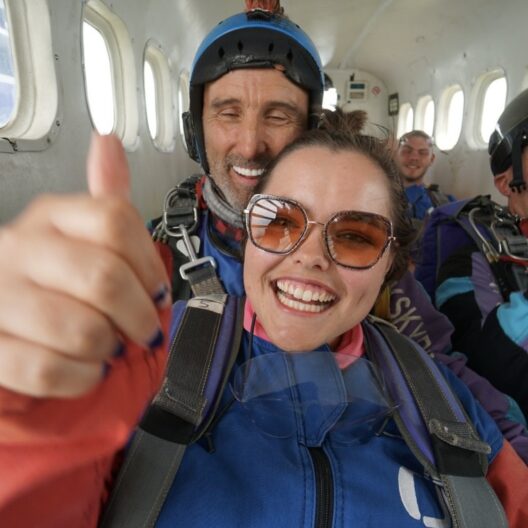 Tilly holding a thumbs up while on the plane before her skydive
