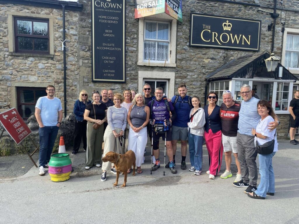 Rob and supporters smile outside pub to celebrate Rob completing his double three peaks challenge. 