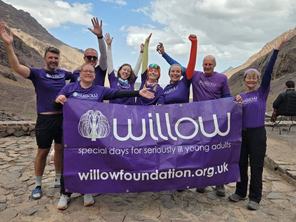 Willow trekkers with their hands up, smiling and holding the Willow banner