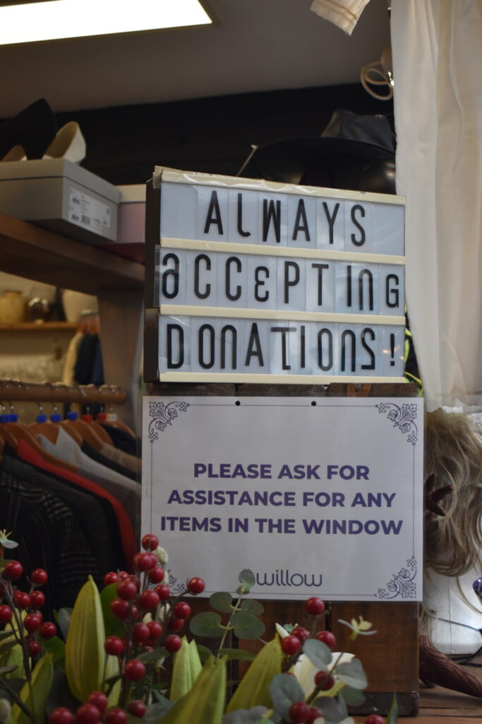 Sign in Willow Hitchin shop window reading "Always accepting donations!"