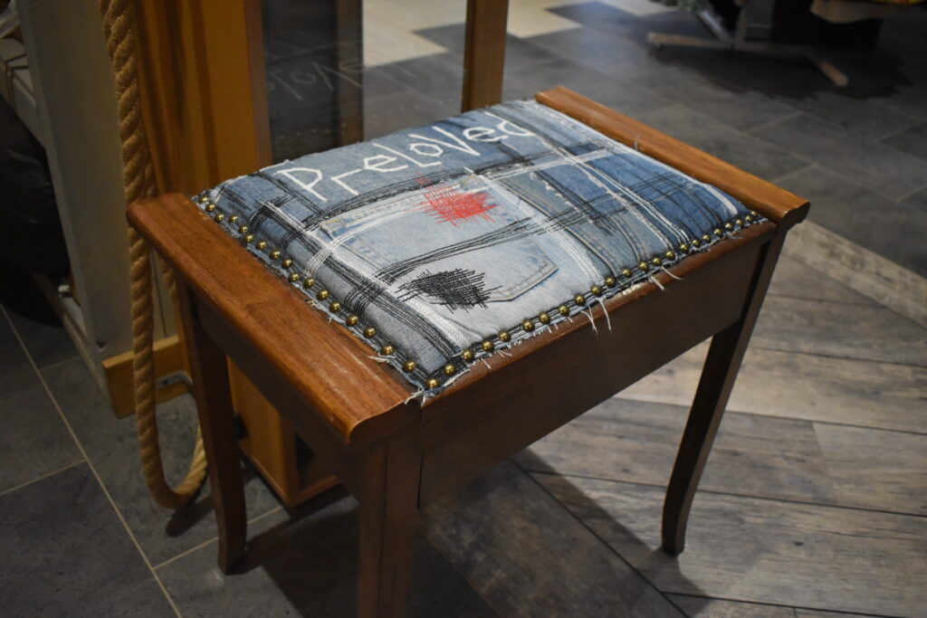 Chair inside Willow Biggleswade shop, cover reads "Preloved" in hand-sewn letters.