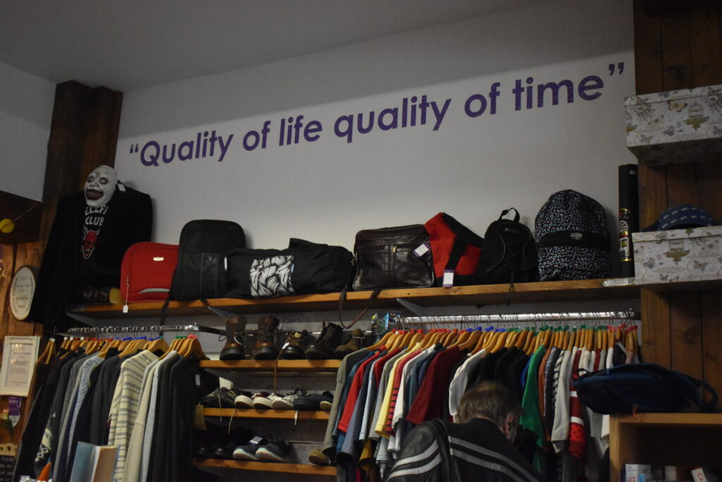 Inside Willow's Letchworth charity shop capturing a rack of shoes, bags, and clothing, with wall stickers reading "Quality of life quality of time".