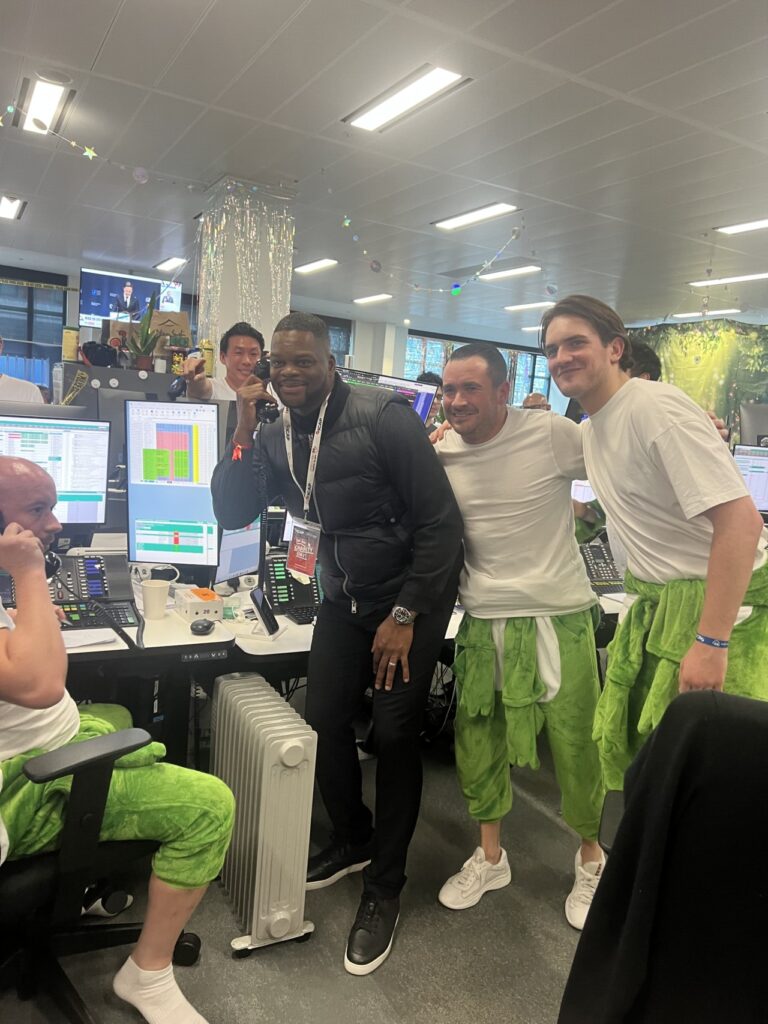 Marlon Harewood answering the phone at ICAP Charity Day 2025 with trading teams in costumes
