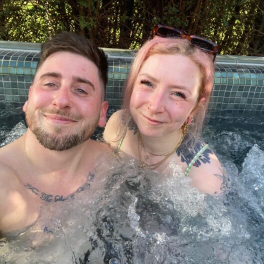 An image of a man and woman in a hot tub, smiling to the camera.