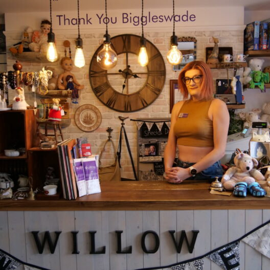 Rose, a transgender woman with pink hair, stand behind the till in our Biggleswade shop.